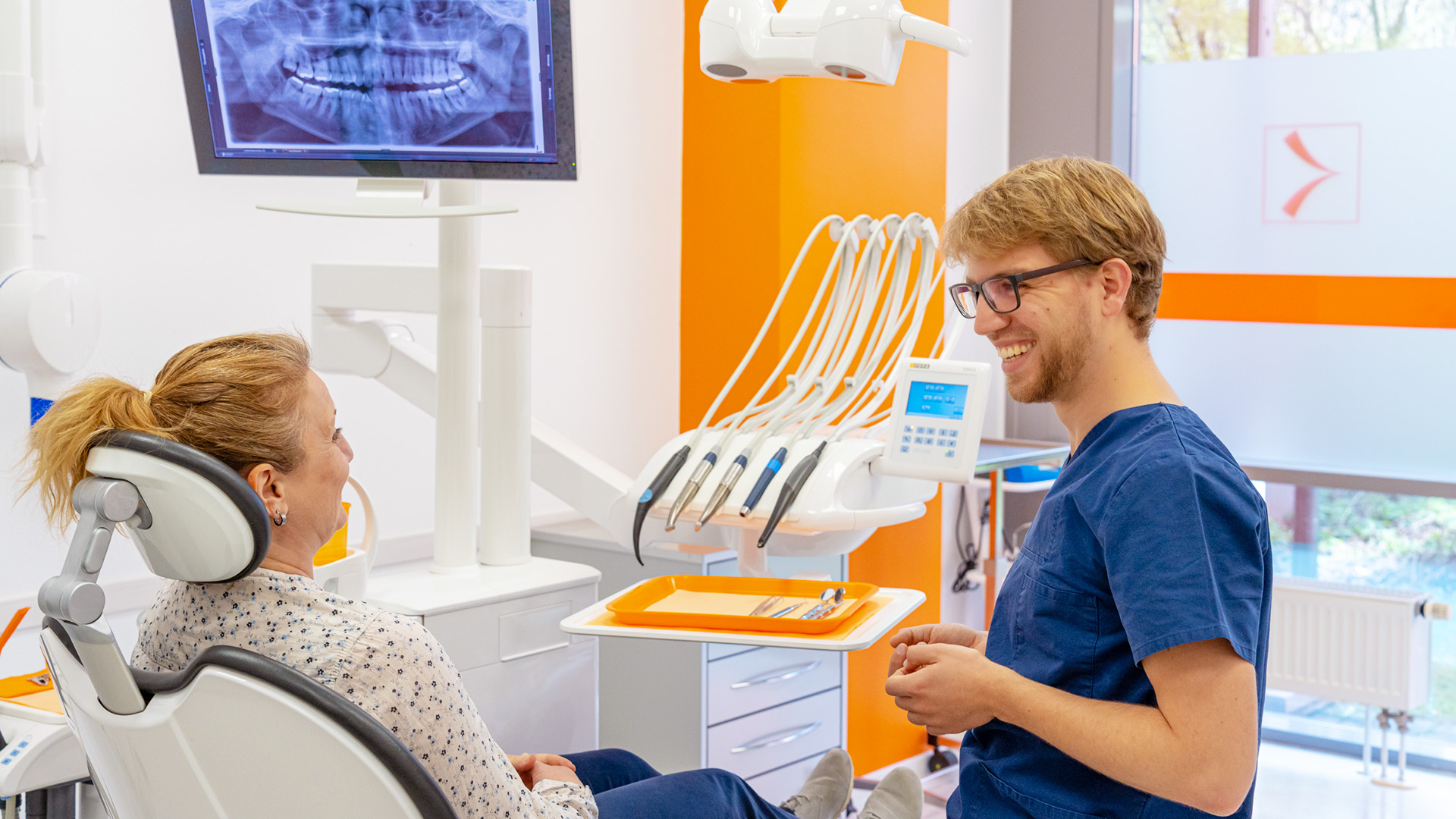 Zahnarzt der ZTK Zahngesundheit im Gespräch mit einer Patientin im Behandlungszimmer.